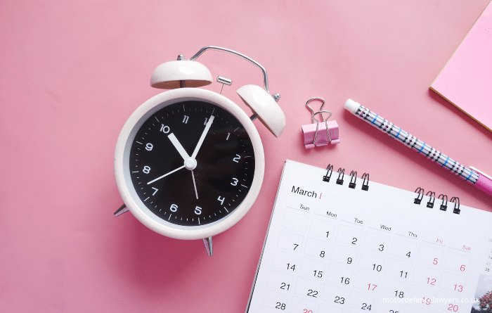 Calendar and alarm clock on pink background